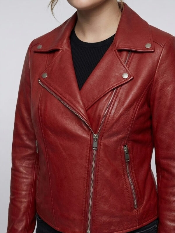 Close-up of asymmetrical zipper closure and collar on women's red leather jacket.
